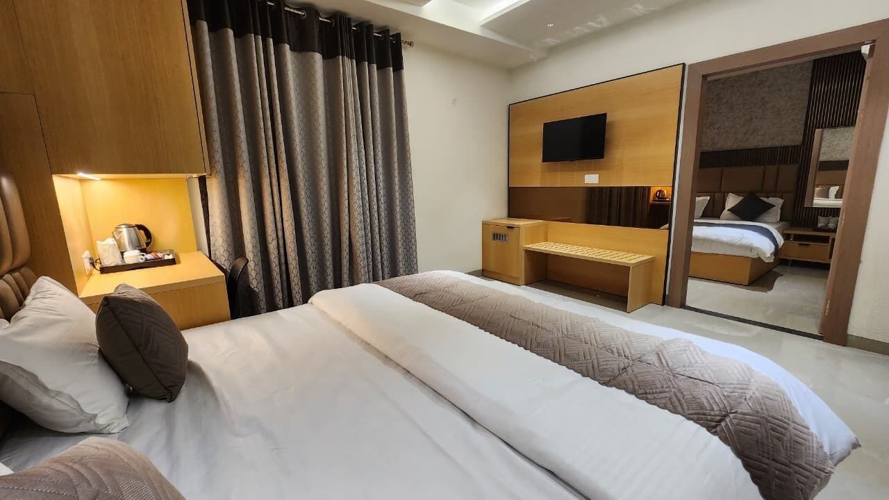 A hotel room with a bed, a desk, a TV, and a mirror.