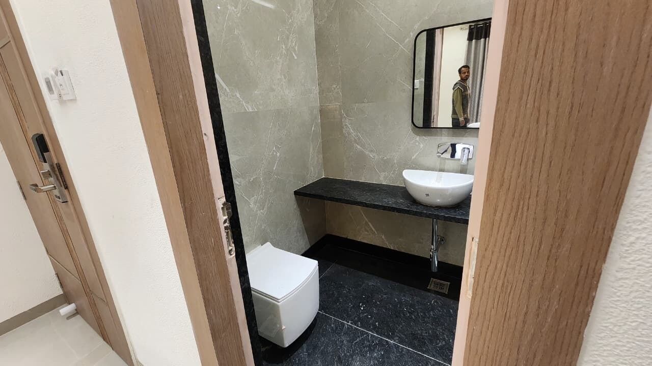 A bathroom with a white toilet, a sink with a mirror above it, and a black countertop.