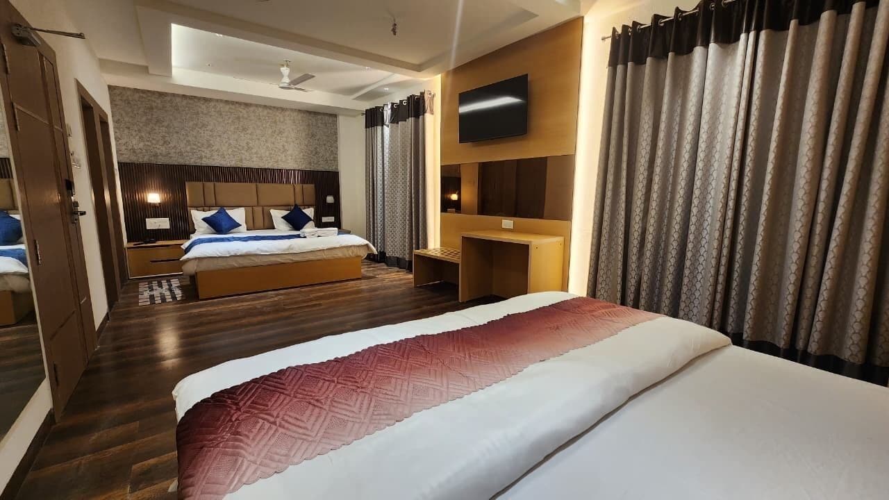 A hotel room with a large bed, a desk, a TV, and a shower area.