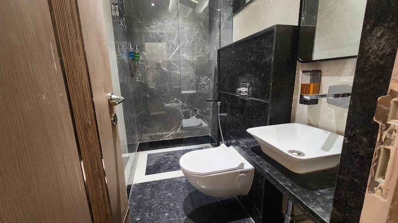 A modern bathroom with a marble floor, a white toilet, and a black sink.