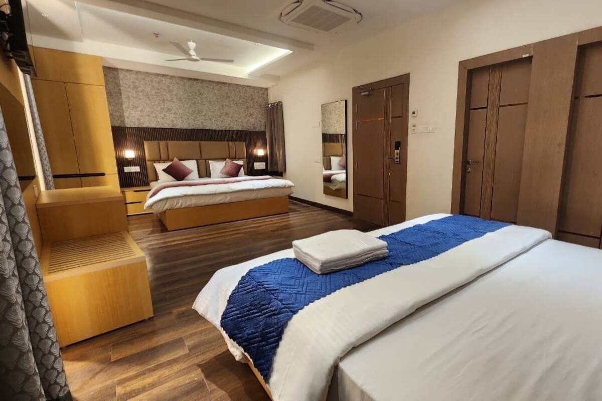 A hotel room with a large bed, a separate seating area, a wardrobe, and a ceiling fan.