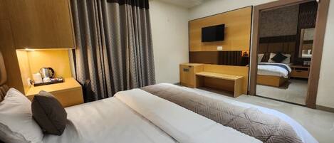 A hotel room with a bed, a desk, a TV, and a sliding door leading to a bathroom.