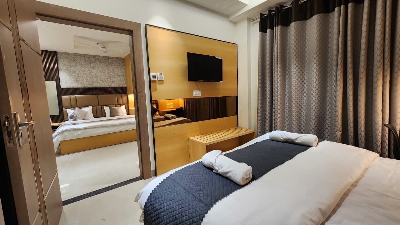 Una habitación de hotel con cama, escritorio, televisor y espejo.
