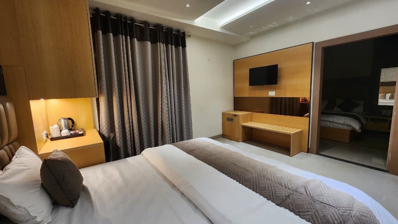 Ett modernt hotellrum med en säng, ett nattduksbord, en TV och en skjutdörrsgarderob.