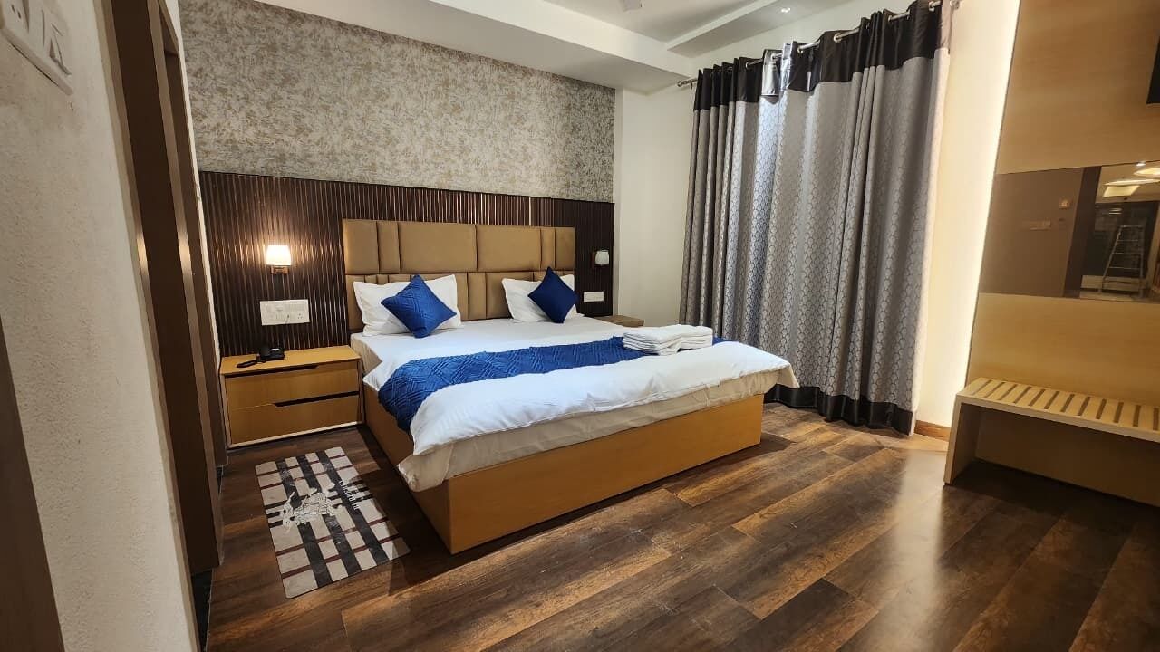 Habitación de hotel moderna con una cama grande, cabecera de madera y una mesita de noche con lámpara.