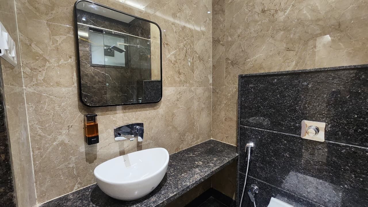 A bathroom with a white sink, a mirror, and a black tiled wall.