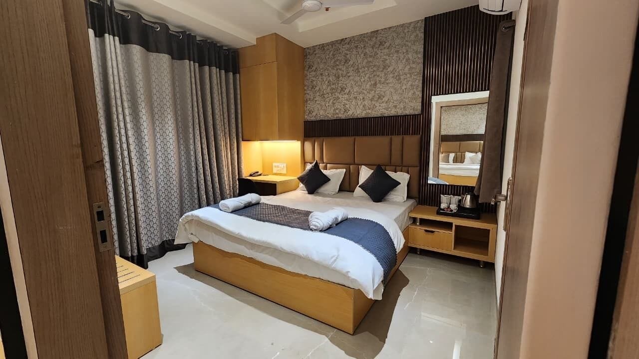 A hotel room with a large bed, bedside tables, a mirror, and a patterned wall.