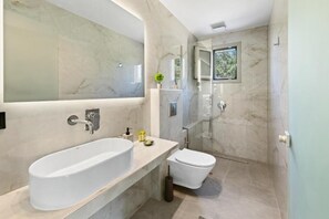 Ein modernes Badezimmer mit einer großen Badewanne, einer Toilette und einer gläsernen Dusche.