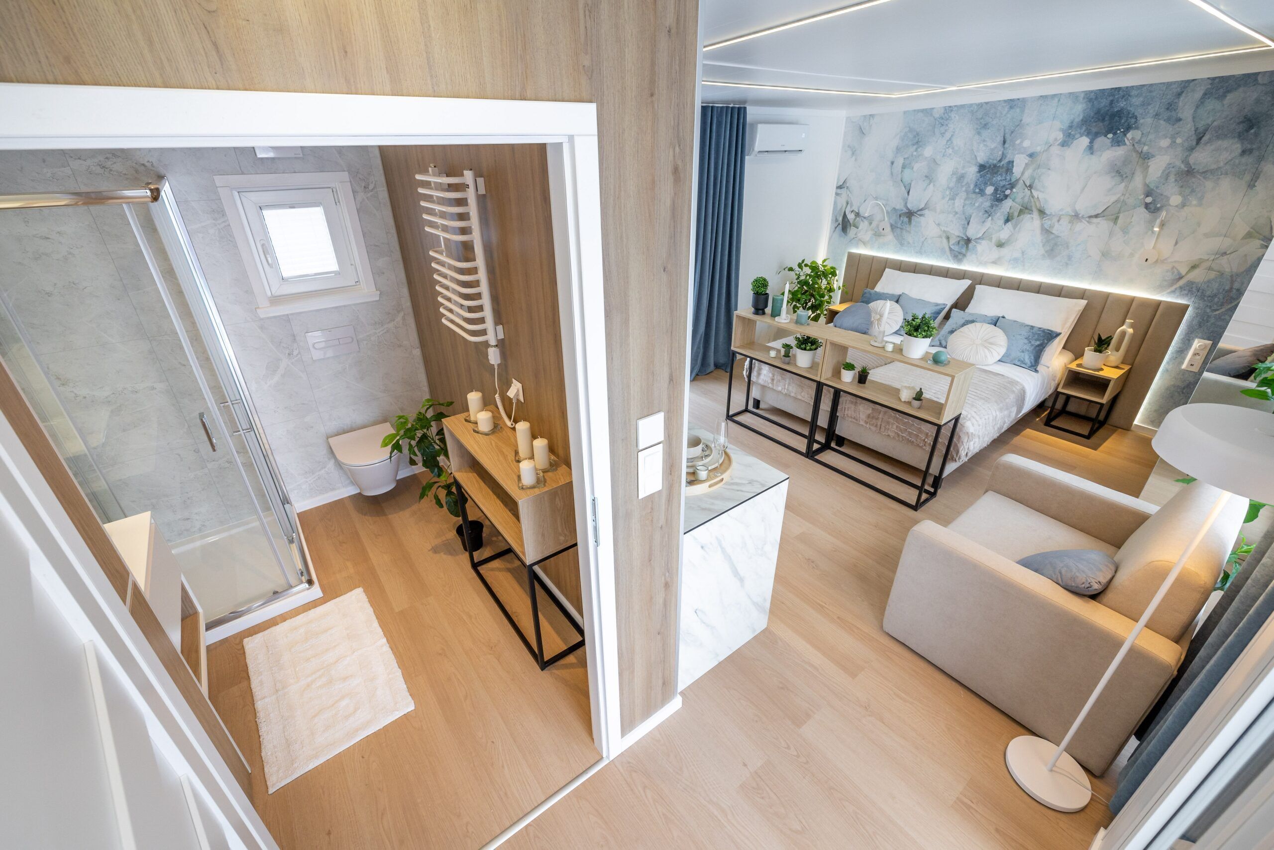 A modern bedroom with a bed, bedside tables, a sofa, and a large window.