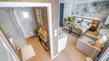 A modern bedroom with a bed, bedside tables, a sofa, and a large window.