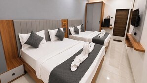 A hotel room with two beds, a TV, a mirror, and a wooden shelf. - Hotel Bhujiyo Hills (Bhuj)
