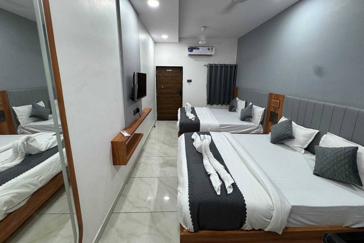 A hotel room with two beds, a TV, a ceiling fan, and a mirror.