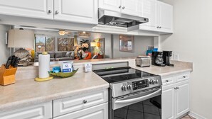A kitchen with white cabinets, a stove, a toaster, and a coffee maker. - 🌊🌴Geaux Coastal | Charming 2BR Home | Steps to Private Beach Access (Navarre)