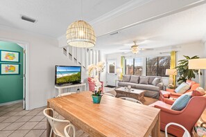 Ein Wohnzimmer mit einem Holzesstisch, einem Fernseher und einem Sofa.
