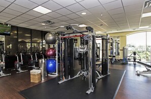 Un gimnasio con varios equipos de ejercicio, incluyendo máquinas de pesas y pesas libres.