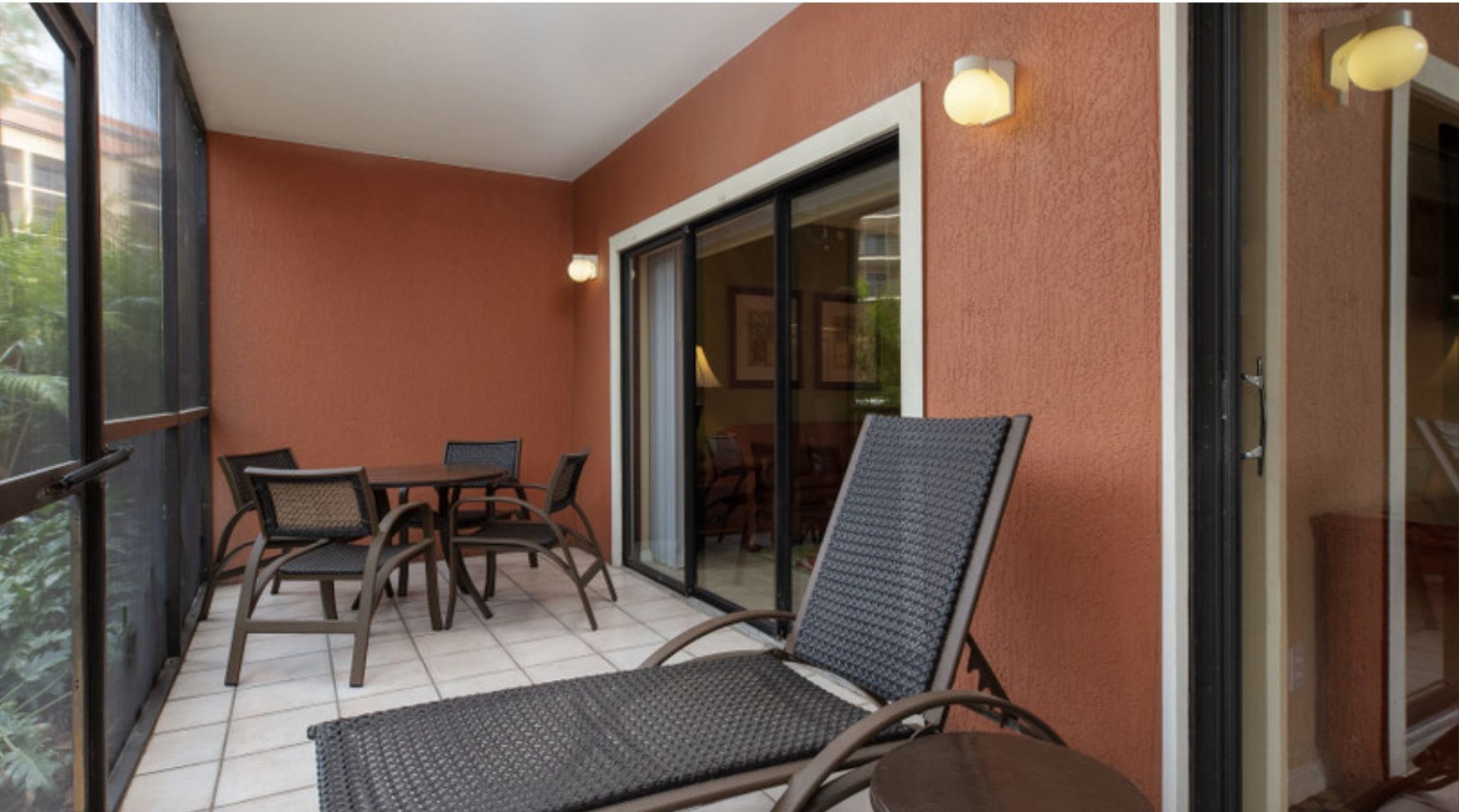 A balcony with a table and chairs, a chair, and a sliding glass door.