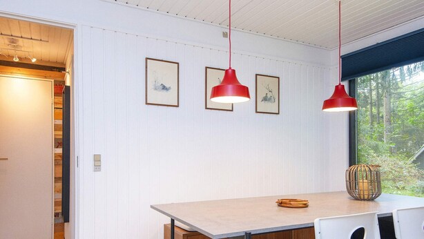 A dining area with a wooden table, two chairs, and red pendant lights. - 6 Person Holiday Home in Ans By (Ans)