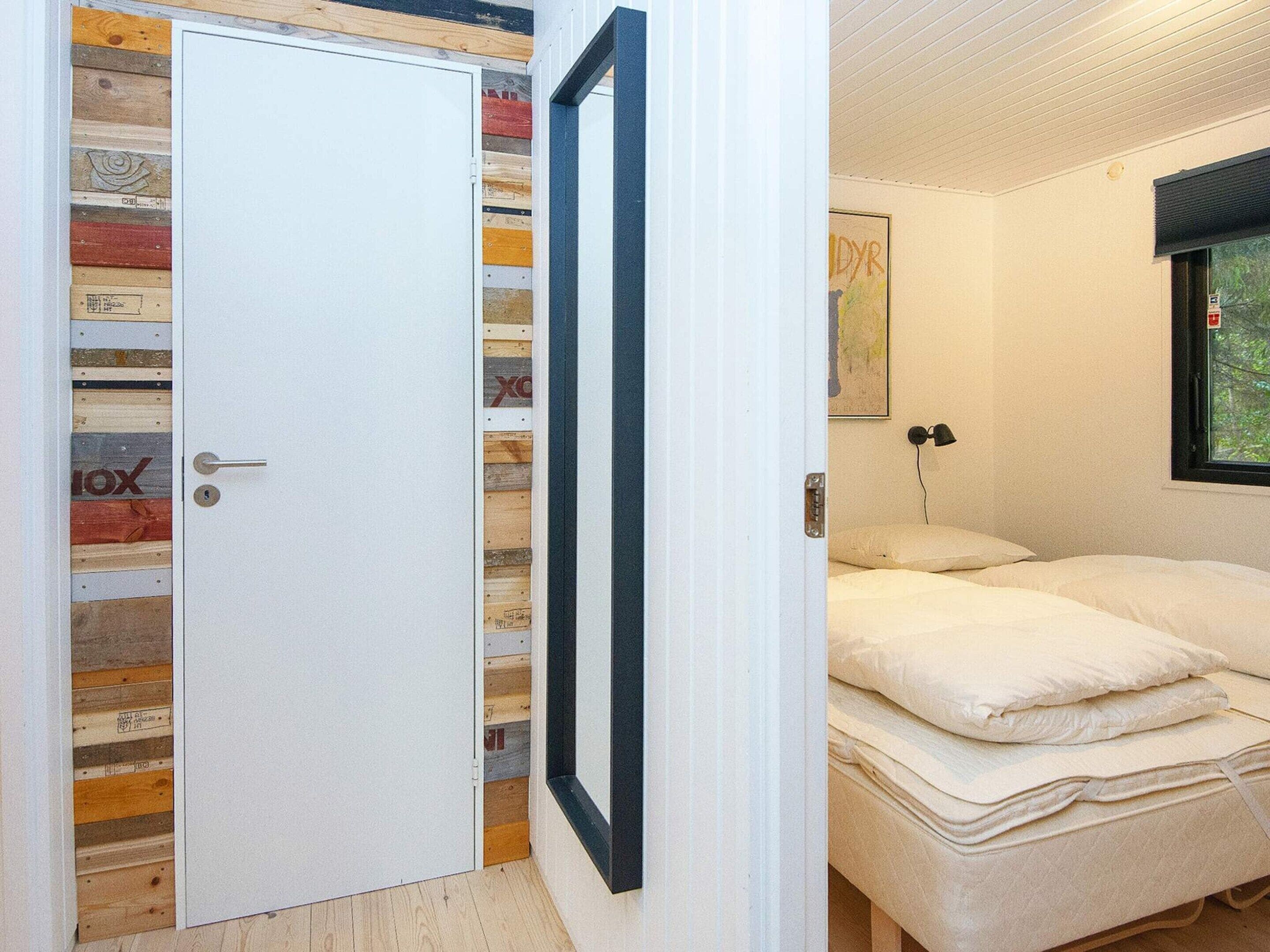 Una habitación con una cama, una puerta blanca y un panel de madera en la pared.