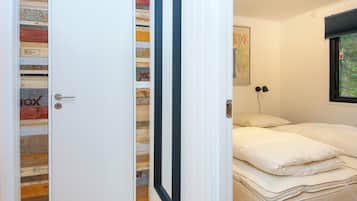 Una habitación con una cama, una puerta blanca y un panel de madera en la pared.
