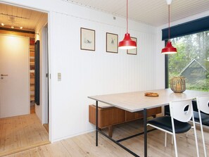 A dining area with a wooden table, two chairs, a red pendant light, and framed pictures on the wall. - 6 Person Holiday Home in Ans By (Ans)
