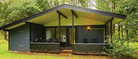 A cabin with a covered porch, a dining area, and a kitchen.