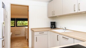 A compact kitchen with white cabinets, a wooden countertop, a coffee maker, and a window with a view of greenery. - 6 Person Holiday Home in Ans By (Ans)