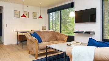 Una sala de estar moderna con un sofá, una mesa de centro, un televisor y cuadros en la pared.