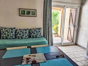 Une pièce avec un canapé, une table et une vue sur l’extérieur, visible à travers une porte.