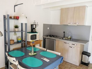 Une cuisine compacte équipée d’un four à micro-ondes, d’une cuisinière, d’un évier et d’une petite table à manger avec des chaises.