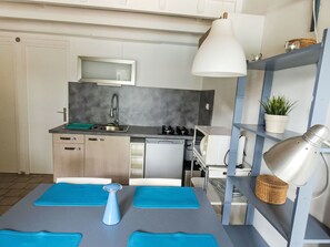 Une cuisine moderne équipée d’un four à micro-ondes, d’un évier, d’une cuisinière et d’un luminaire suspendu.