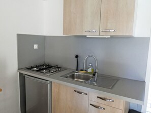 Eine Küche mit Gaskochfeld, Spüle aus Edelstahl und Holzschränken.