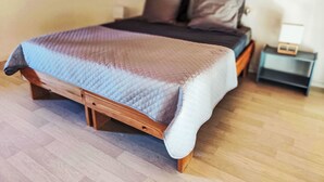 A bed with a quilt, wooden frame, and a nightstand with a lamp. - "La Cigale" mit Schwimmbad by Interhome (Les Arcs sur Argens)