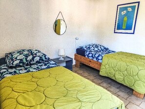 Une chambre avec deux lits, une table de chevet, une lampe, un tableau encadré et un miroir fixé au mur.