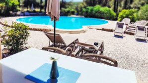 A poolside area with lounge chairs, a table with a bottle, and an umbrella. - "La Cigale" mit Schwimmbad by Interhome (Les Arcs sur Argens)