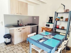 Eine kleine Küche mit Mikrowelle, Wasserkocher und einem Tisch mit blauen Tischsets.