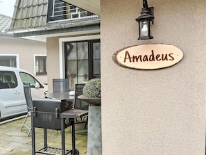 Ein Haus mit Grill, einem Auto und einem Schild mit der Aufschrift 'Amadeus'.