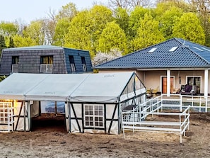 Ein Gebäude mit blauem Dach, einem überdachten Außenbereich mit weißem Zelt und einem weißen Zaun.