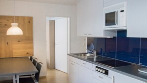 A modern kitchen with white cabinets, a microwave, a sink, and a dining area with a table and chairs.