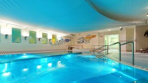 An indoor swimming pool with clear water, a diving board, and a mural on the wall.