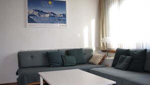 Et værelse med en grå sofa, et hvidt bord og et billede på væggen.