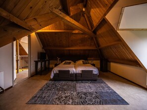 A bedroom with a sloped ceiling, a double bed, a small bedside table, a lamp, and a patterned rug. - Oranjezon B by Interhome (Vrouwenpolder)