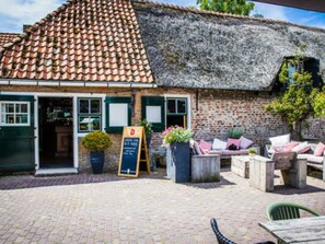 A rustic building with a tiled roof, a brick wall, and a wooden bench outside. - Oranjezon B by Interhome (Vrouwenpolder)