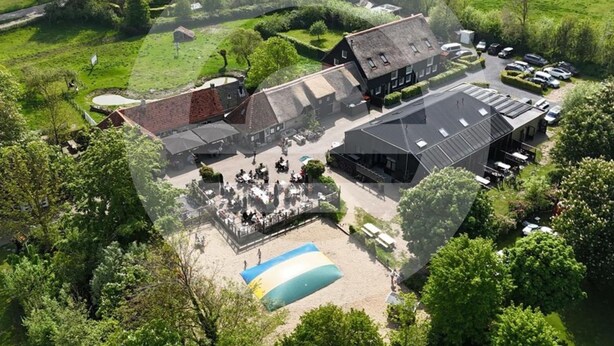 Vue aérienne d’une propriété dotée d’une piscine, d’un espace de détente extérieur abrité et d’un parking.