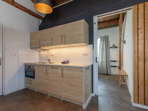 A modern kitchen with wooden cabinets, a built-in oven, and a pendant light. - Pleinzicht 6c by Interhome (Koudekerke)
