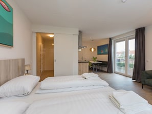 Ein Hotelzimmer mit drei Betten, einem Essbereich und Blick ins Freie.
