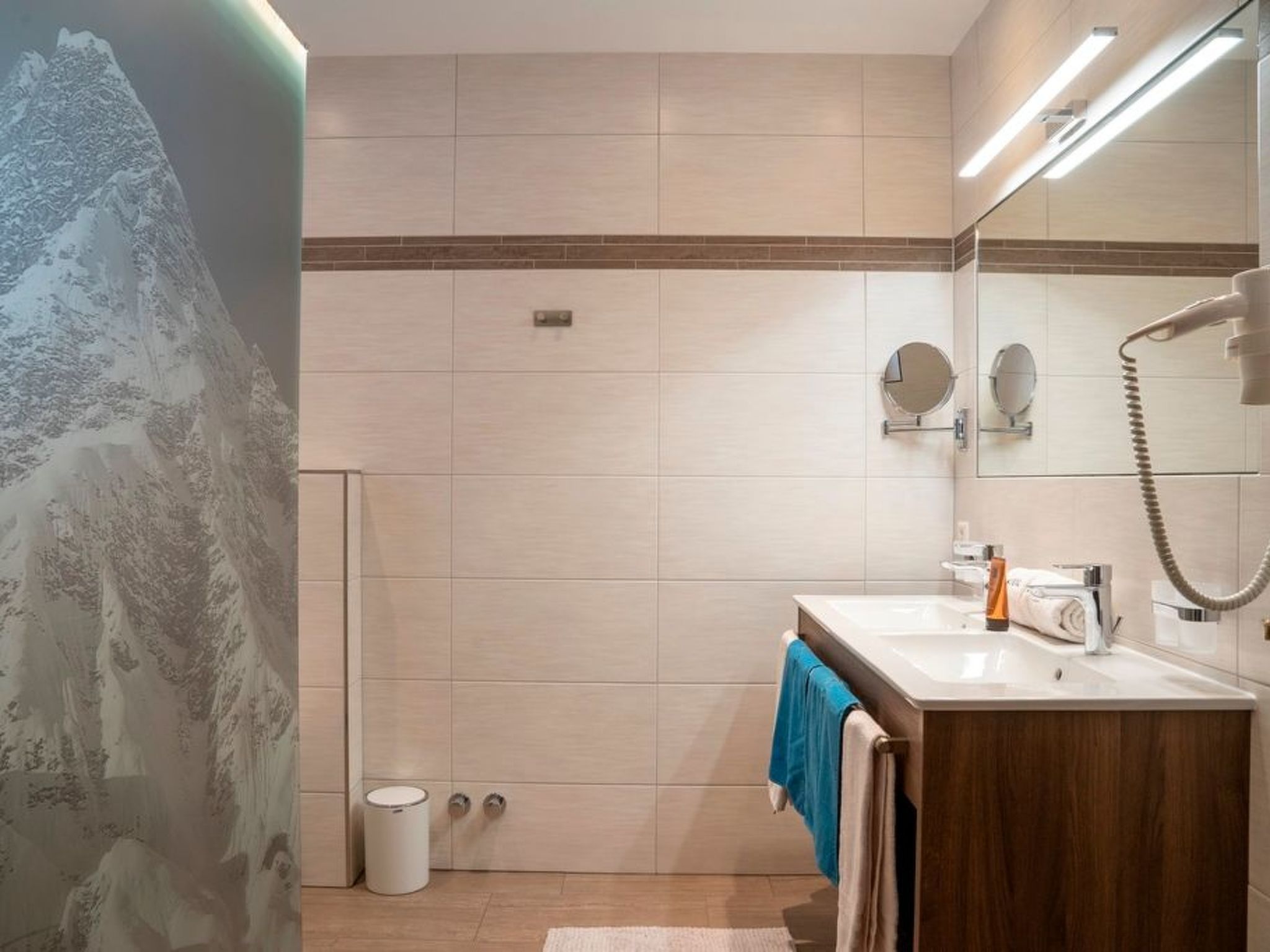 Une salle de bain moderne avec un grand miroir, un lavabo et un porte-serviettes.