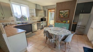Een keuken met een eettafel, stoelen, een koelkast en een magnetron.