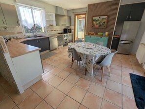Eine Küche mit Esstisch, Stühlen, Kühlschrank und Mikrowelle.