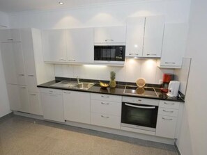 A modern kitchen with white cabinets, a black countertop, a microwave, a sink, and a coffee maker. - Appartementhaus Cristal, (Samnaun-Dorf) by Interhome (Samnaun)