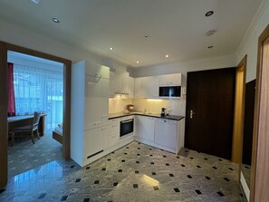 A modern kitchen with white cabinets, a built-in microwave, and a tiled floor. - Appartementhaus Cristal, (Samnaun-Dorf) by Interhome (Samnaun)